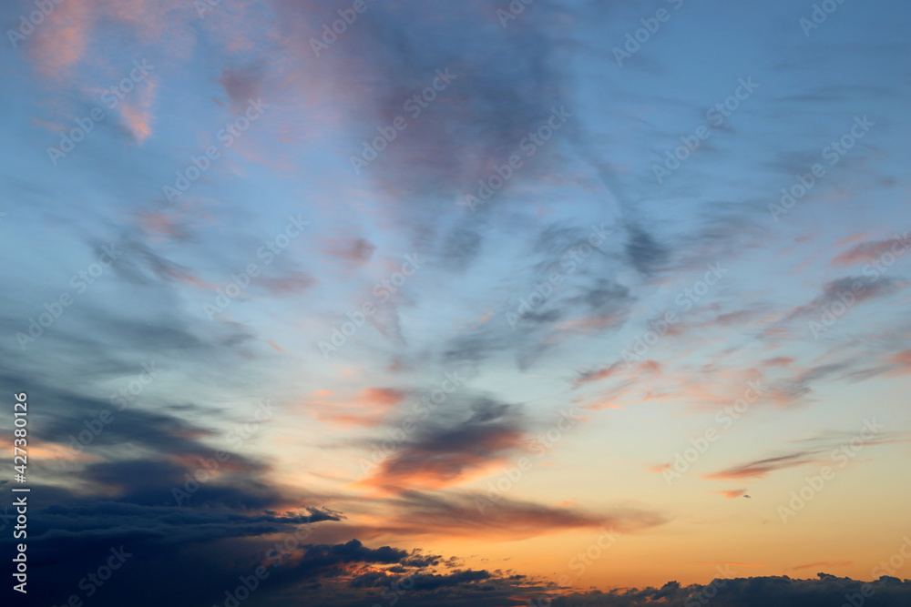 Sunset on colorful sky, clouds in the pink and orange sunlight. Picturesque landscape for background with soft colors