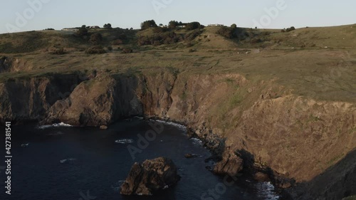 Person at end of coastal cliff at sunset