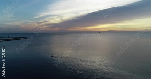 Person paddle boarding in the ocean during the sunrise