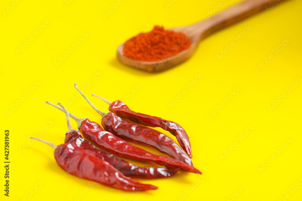 Chilli powder in wooden spoon with dry red chilly on yellow background. Chilli powder in wooden spoon with dry red chilly on yellow background.