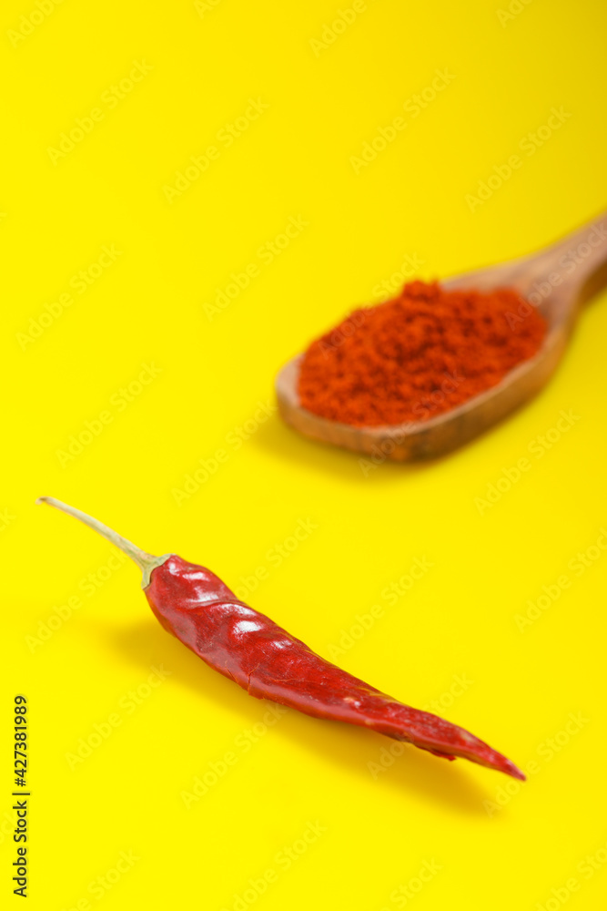Chilli powder in wooden spoon with dry red chilly on yellow background. Chilli powder in wooden spoon with dry red chilly on yellow background.