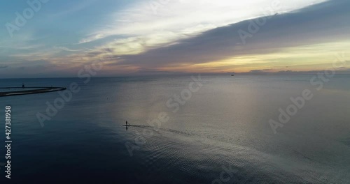 Person paddle boarding in the ocean during the sunrise 