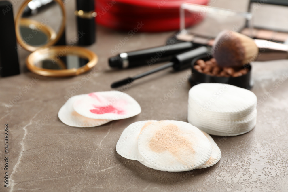 Dirty cotton pads and cosmetic products on grey table Dirty cotton pads and cosmetic products on grey table