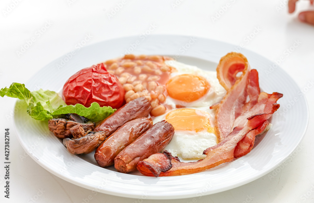 traditional English breakfast with sunny side up egg,toast,tomatoes,bacon,sausage and baked beans.