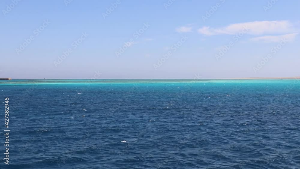 Seascape in motion, panoramic view of the azure waters of the Red Sea, turquoise coral reefs in the distance, white desert sand on the horizon, red lighthouse in the sea Seascape in motion, panoramic view of the azure waters of the Red Sea, turquoise coral reefs in the distance, white desert sand on the horizon, red lighthouse in the sea