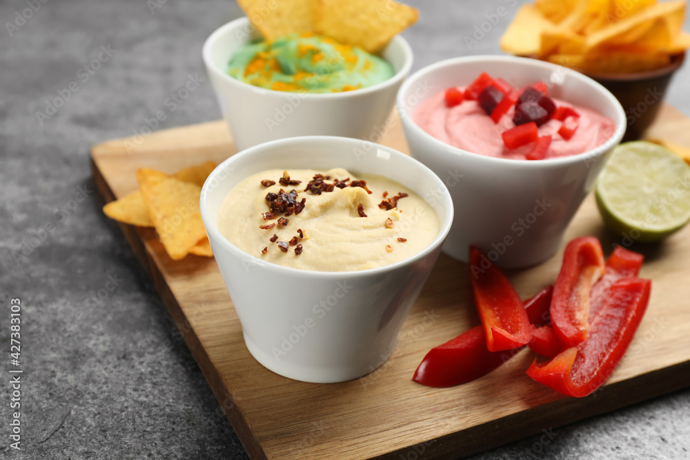 Different kinds of tasty hummus with ingredients on grey table Different kinds of tasty hummus with ingredients on grey table