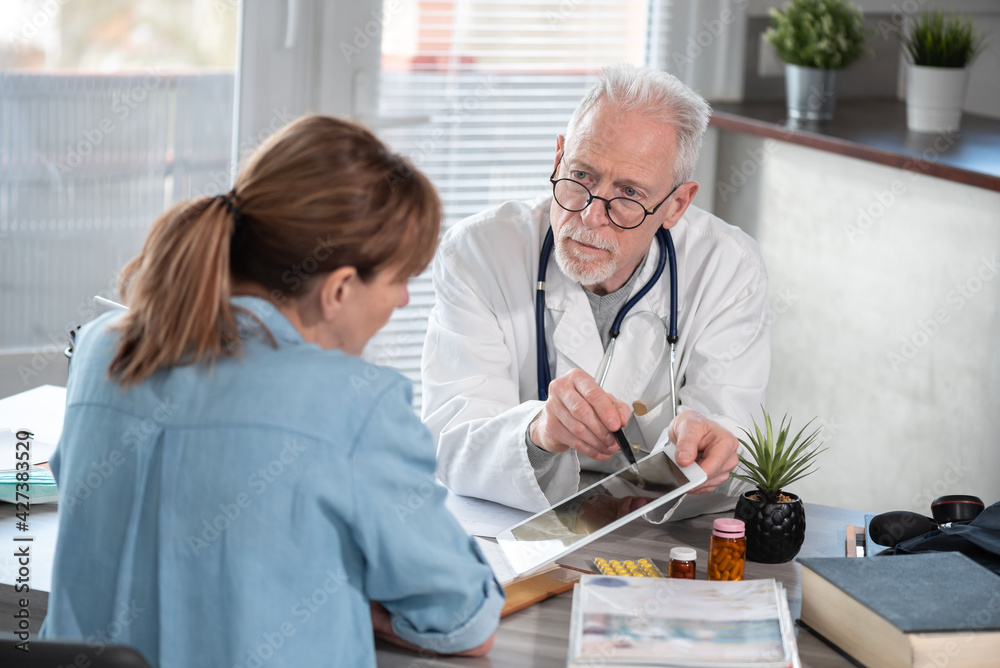 Doctor showing reports on digital tablet to his female patient Doctor showing reports on digital tablet to his female patient