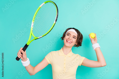 Photo of attractive happy young tennis player woman hold racket ball serve isolated on pastel teal color background © deagreez