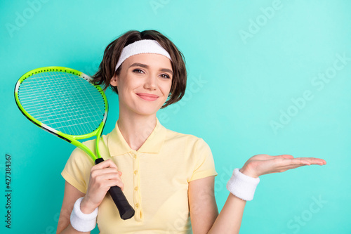 Portrait of attractive sportive cheery girl holding in hand racket copy space on palm isolated over bright teal turquoise color background