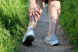 Ankle sprain, woman grabbed her leg while walking on a spring or summer nature. Concept of tired legs, injury on running