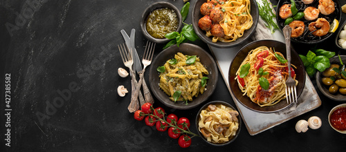 Assortment of Italian pasta with traditional sauces for dinner on dark background.