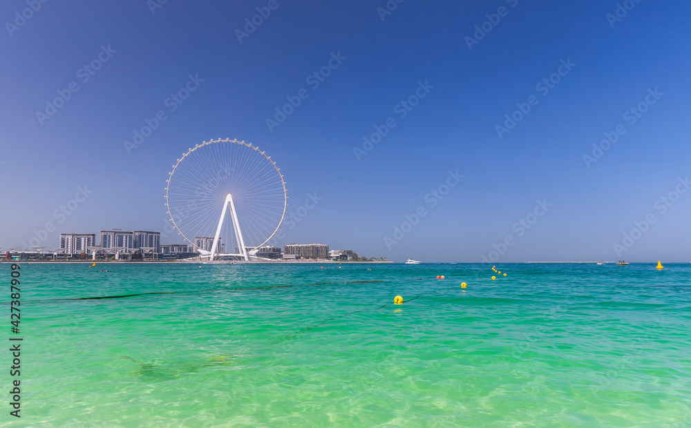 Dubai, UAE - March 04, 2021: Ferris wheel on Dubai Marina beach