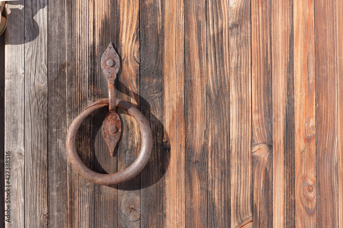 Fotografie Fragment of an old wooden gate with a wrought iron handle with rust stains