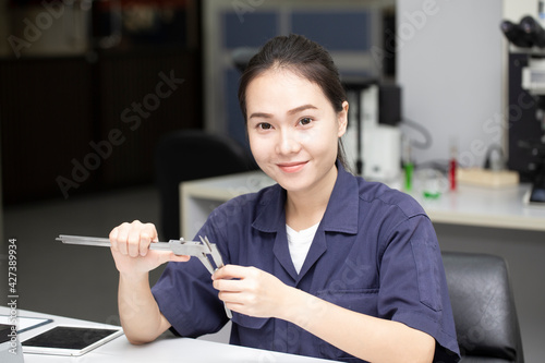 young asian engineer using vernier gauge for measure or chech workpiece, engineering technology or science research concept photo