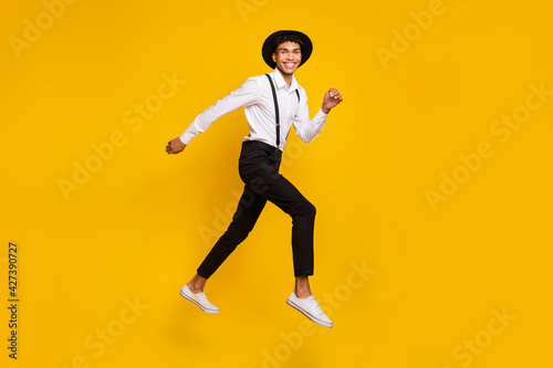Photo of energetic sporty guy jump run wear headwear shirt suspenders footwear isolated yellow color background © deagreez