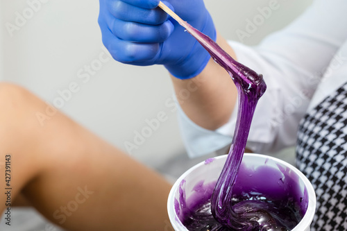 Closeup of Female Beautician Hands Mixing Liquid Colorful Wax in Plastic Container For  Sugaring Proceedure on Female Legs in Salon photo