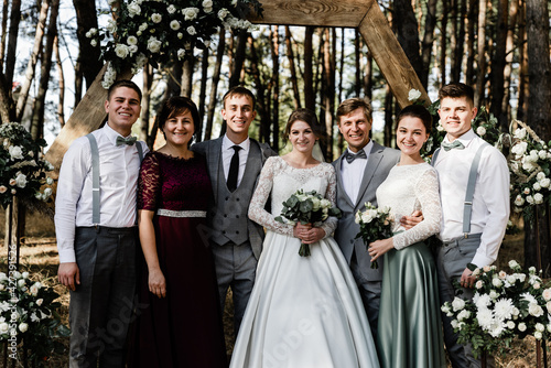 international family. family portrait at the wedding. newlyweds with loved ones. wedding arch. lovely family in beautiful outfits