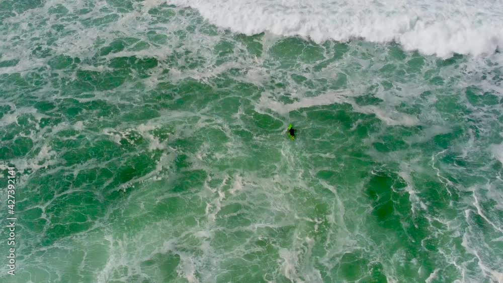 Aerial top-down drone view of surfer trying to catch a wave in strong big waves in Nazare,4k Aerial top-down drone view of surfer trying to catch a wave in strong big waves in Nazare,4k