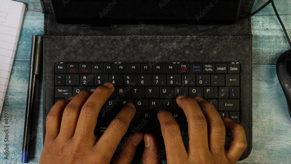 Top view of hands of an Indian man typing in keyboard of mini computer