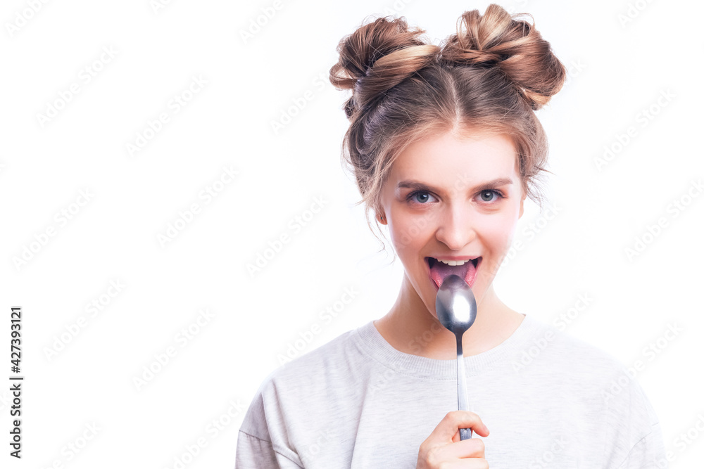 Positive Caucasian Blond Girl Posing in White T-Shirt With Shiny Metal Spoon in Front of The Mouth Against Pure White Positive Caucasian Blond Girl Posing in White T-Shirt With Shiny Metal Spoon in Front of The Mouth Against Pure White