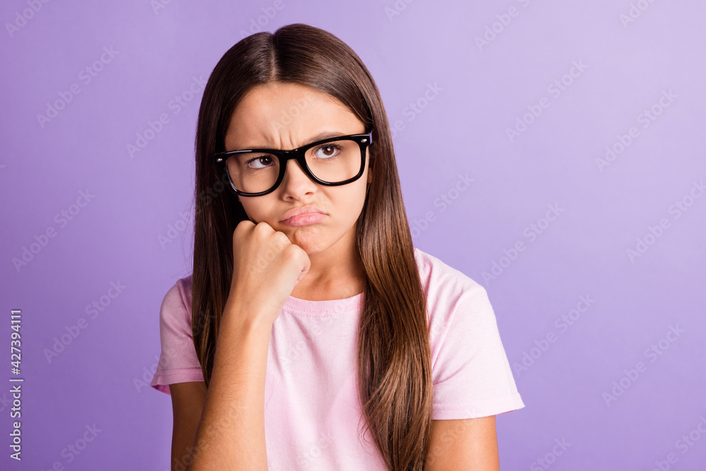 Photo of upset unhappy young girl wear pink t-shirt spectacles fist chin looking empty space isolated violet color background