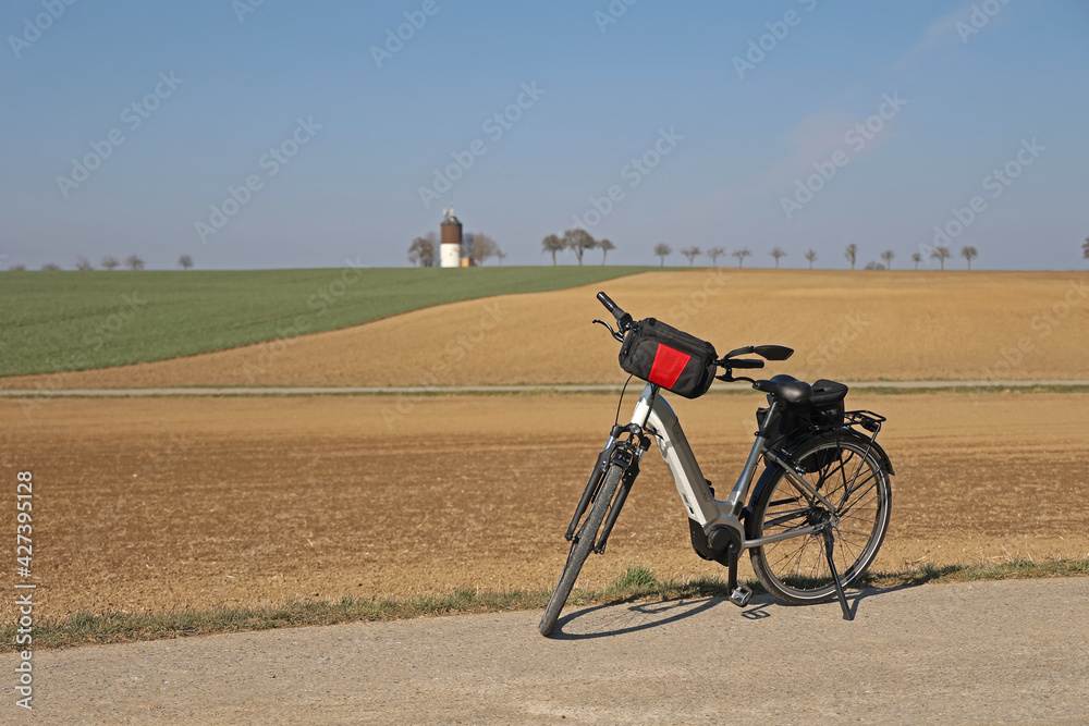 Fototapeta premium The e-bike stands near a plowed field