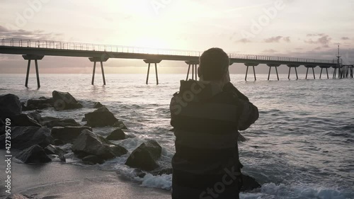 Photographer taking pictures of the sunrise and seascape at the beach