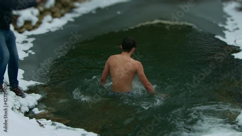 Winter swimming. A young guy dives into cold water. super slow motion