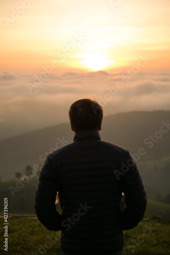man watching sunrise at hilltop