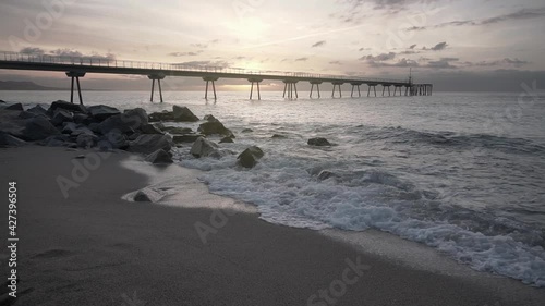 Slow Motion  Footage of a Beautiful sunrise at the beach with waves crashing and a bridge in the background.