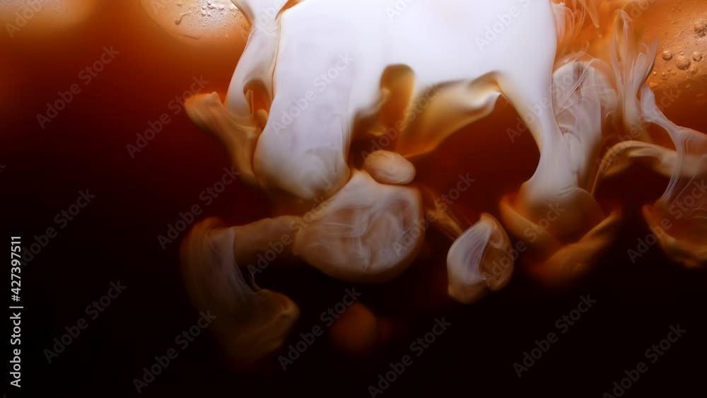 Cream or milk is poured into iced coffee, frappe, frappuccino, iced coffee. Preparing coffee, a refreshing summer drink in the morning. Macro. Close up. Slow motion.
