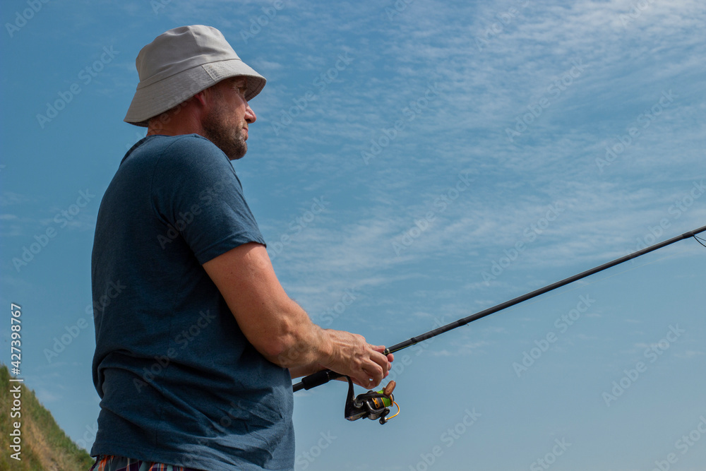 man with a fishing rod in his hands against the blue sky man with a fishing rod in his hands against the blue sky