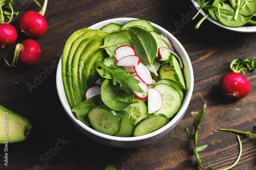 Health vegetarian salad with avocado, radish, spinach and cucumber photo