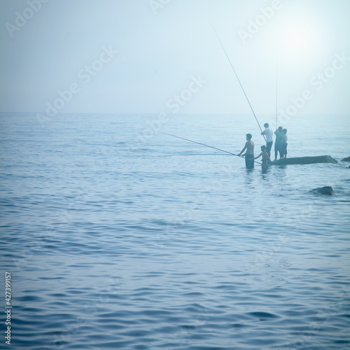 Silhouette of fishermen fishing at sea. Summer leisure, sport, holiday concept.