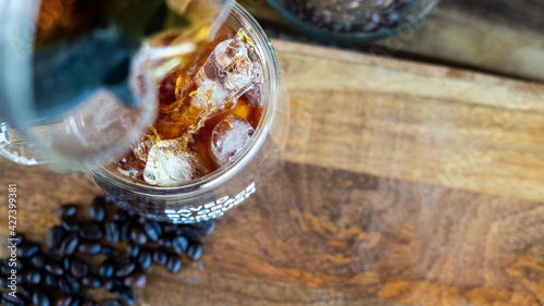 Iced coffee in a doublewall clear glass over wooden table