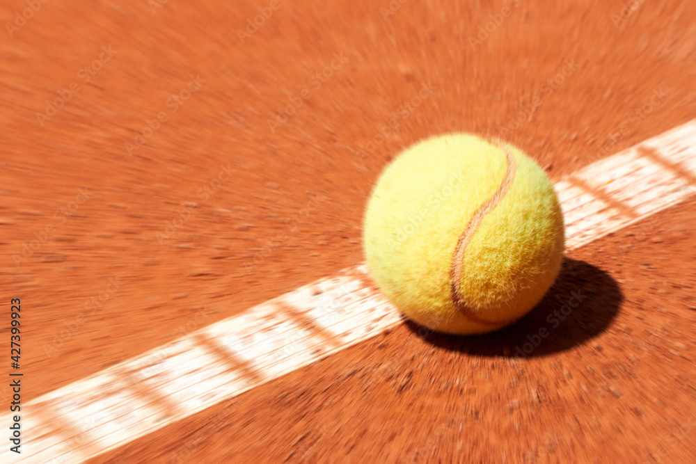 Tennis ball on a clay court outdoors.