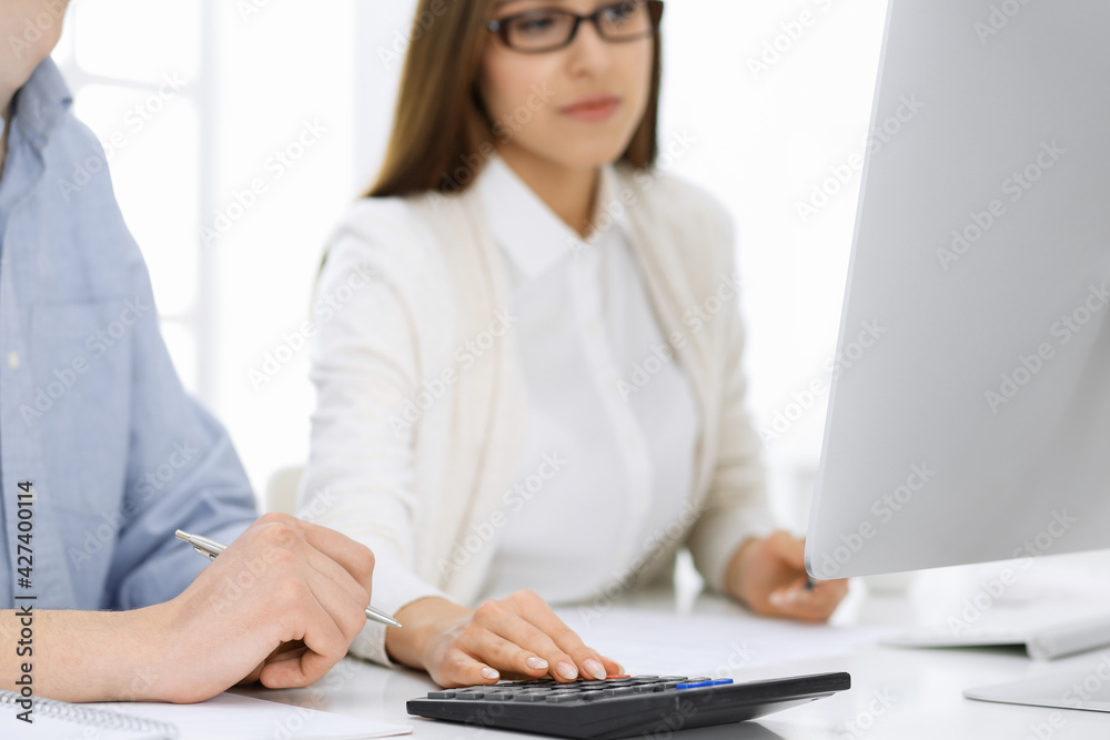 Bookkeeper checking balance with calculator or making finance report, close-up of hands. Tax and audit concepts Bookkeeper checking balance with calculator or making finance report, close-up of hands. Tax and audit concepts