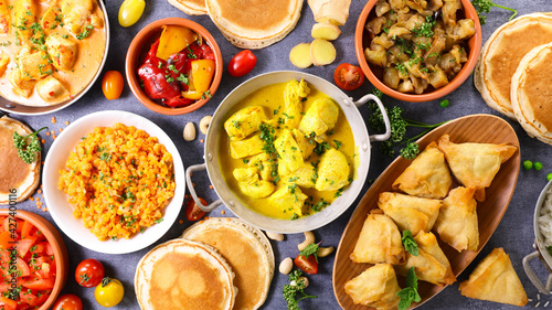 indian food assortment- naan, curry chicken, samosa, dhal lentils