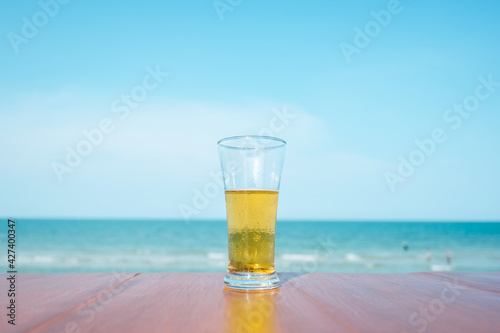 Beer glass on wooden bar table, ocean view with fresh beer on natural background, Happy vacation of the sea