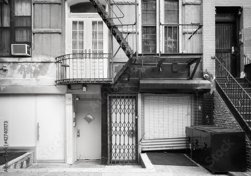 Black and white picture of old building facade with iron fire escape, New York City, USA.