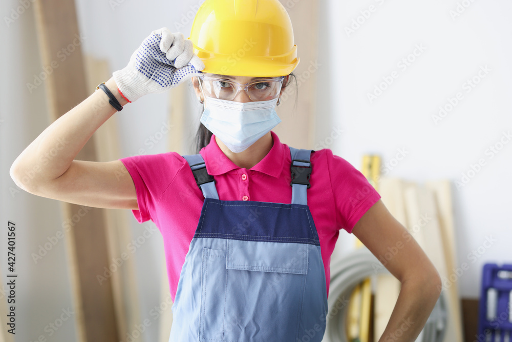 Woman builder in yellow hard hat and protective mask Woman builder in yellow hard hat and protective mask