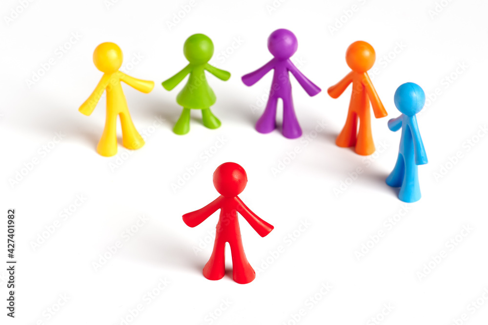 . Toy people Isolated on white background. The red man stands apart from the group. Asociality, sociopathy. Rejected by society, lonely. Development of leadership and social qualities. . Toy people Isolated on white background. The red man stands apart from the group. Asociality, sociopathy. Rejected by society, lonely. Development of leadership and social qualities.