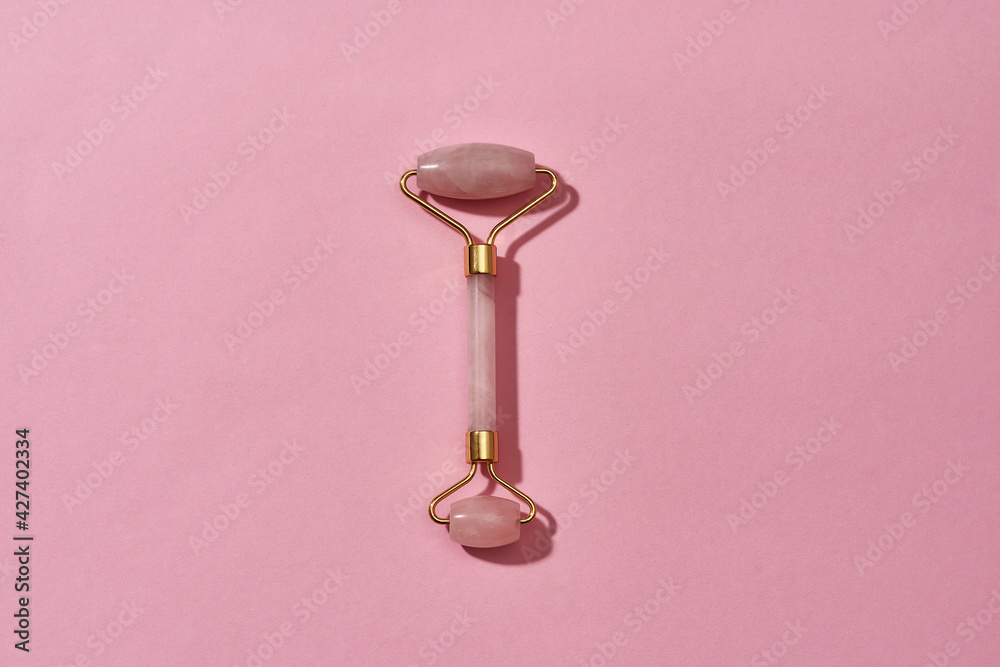 Top view of Rose quartz facial massage roller isolated over pink background Top view of Rose quartz facial massage roller isolated over pink background