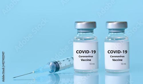 Two vials with a vaccine, a syringe on a blue background.The concept of medicine, healthcare and science.Coronavirus vaccine.Copy space for text..