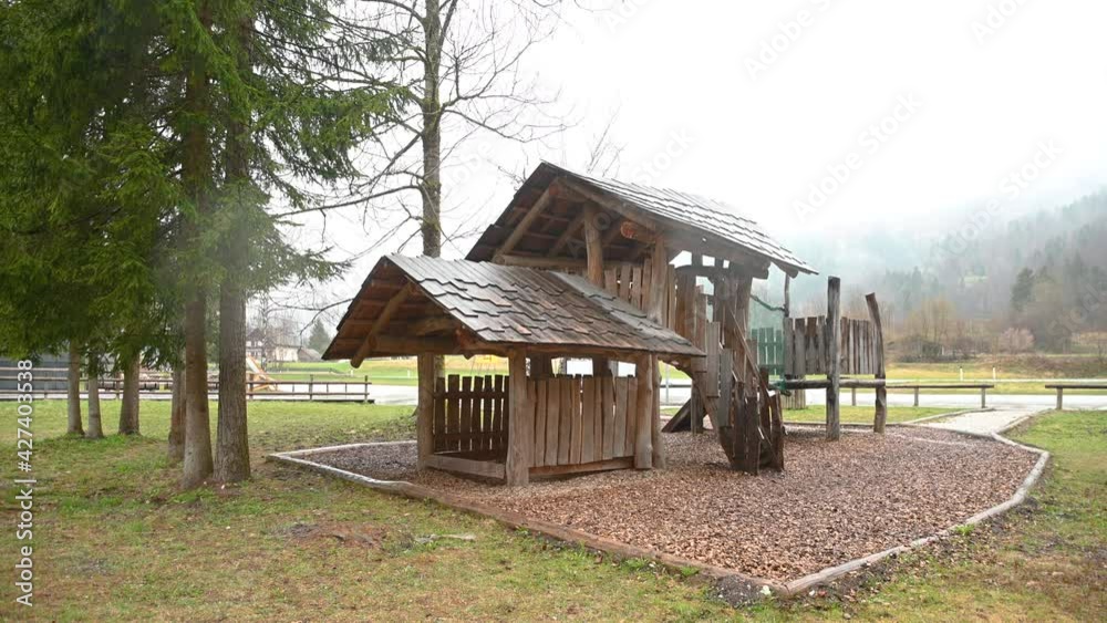 Wooden playground for kids in the park. Gloomy and rainy day without people. Static shot, wide angle Wooden playground for kids in the park. Gloomy and rainy day without people. Static shot, wide angle
