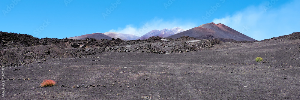 Mount Etna in Sicily near Catania, Tallest active volcano in Italy and whole Europe. Panoramic banner composition. Traces of volcanic activity, steam from craters.