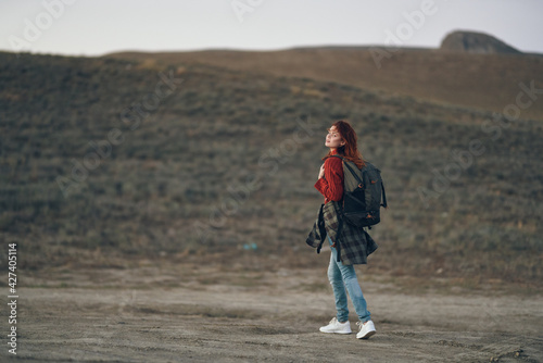 woman traveler in a red jeans sweater with a backpack on her back in the mountains © SHOTPRIME STUDIO