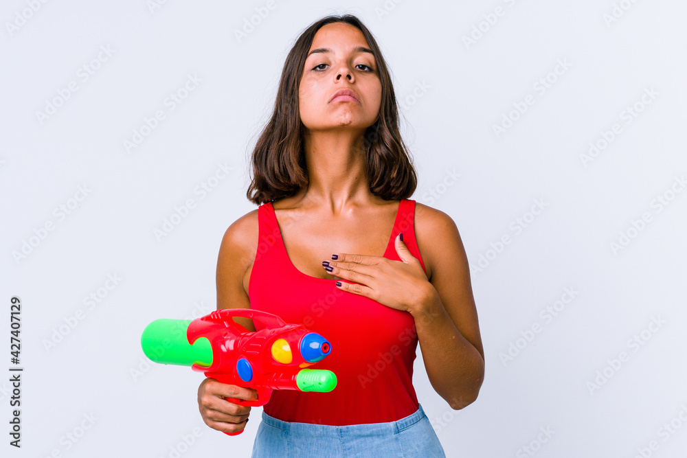 Young mixed race woman holding a water gun isolated taking an oath, putting hand on chest. Young mixed race woman holding a water gun isolated taking an oath, putting hand on chest.