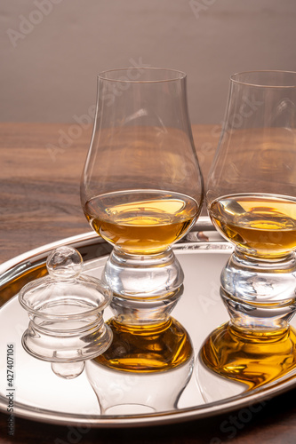 Tasting glasses of single malt scotch whisky served on steel mirror tray with reflection