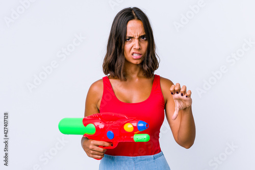 Young mixed race woman holding a water gun isolated showing thumb down and expressing dislike.